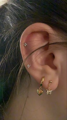 a close up of a person's ear with two small heart shaped earrings on it