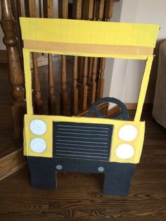 a yellow and black toy truck sitting on top of a wooden floor next to stairs