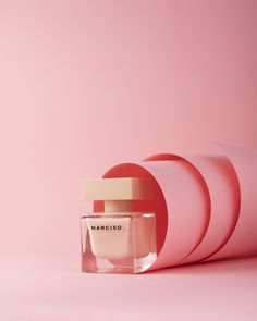 a bottle of perfume sitting on top of a pink surface