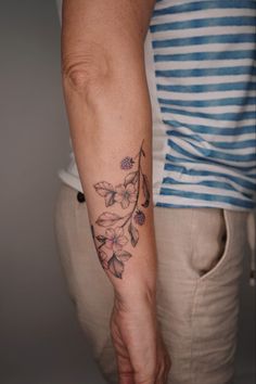 a woman's arm with a flower tattoo on the left side of her arm