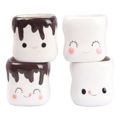 three ceramic cups with faces painted on them, one is white and the other is brown