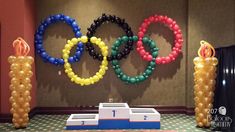 balloons are arranged in the shape of olympic rings next to a podium with a flag on it