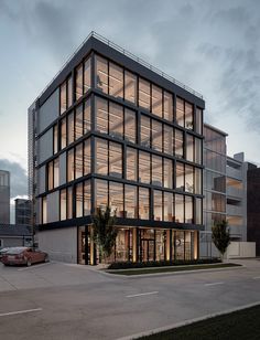 a large glass building with lots of windows on it's sides and cars parked in the parking lot