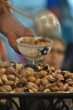 a bowl filled with lots of nuts on top of a metal tray next to people