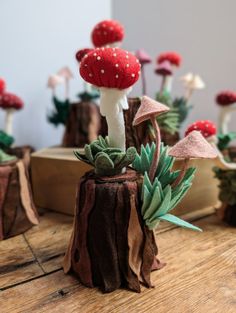 small red and white mushrooms on top of a wooden table next to other fake plants