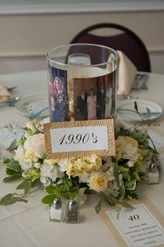 a table with flowers and pictures on it at a wedding or other function in the reception room