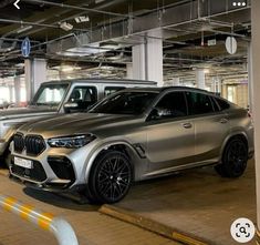 two cars parked in a parking garage next to each other on the floor and one is silver