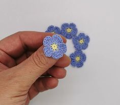 a hand holding a crocheted flower with four petals on it's side