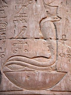 an ancient egyptian carving with birds and symbols on it's face, in front of a stone wall