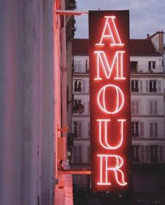 a neon sign that reads amour on the side of a building in paris