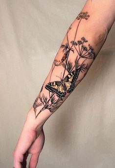 a woman's arm with a butterfly and flowers tattoo on the left inner arm