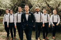 a group of men standing next to each other wearing suits and bow ties in front of trees