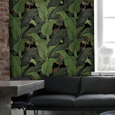 a living room with a couch, table and large wallpapered plant design on the wall