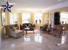 a living room filled with lots of furniture next to two large windows on the wall