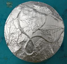 a round metal object sitting on top of a blue surface with peeling paper covering it