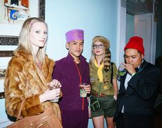 three men and two women dressed in costume posing for the camera with one holding a drink