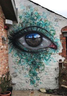 an eye painted on the side of a building with blue and green paint all over it