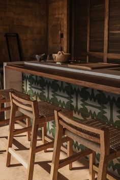 three wooden benches sitting next to each other in front of a tiled wall and counter