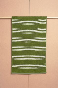 a green and white towel hanging on a clothes line next to a pink wall in the bathroom