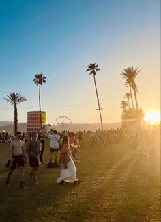 a group of people standing on top of a lush green field next to palm trees