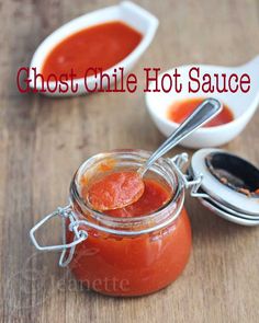 a jar of tomato sauce with two spoons next to it on a wooden table