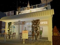 an open restaurant at night with lights on the roof and tables in front of it