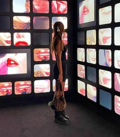 a woman standing in front of a wall with multiple tvs on it's walls