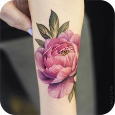 a woman's arm with a pink flower on it and a bee in the middle