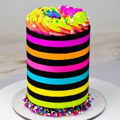 a multi - colored striped cake with sprinkles on top