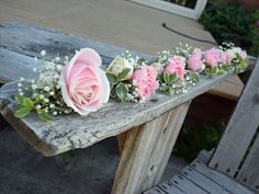 pink roses and baby's breath are arranged on a bench