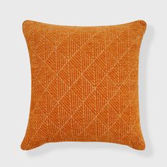 an orange pillow with diamond pattern on the front and back, sitting on a white surface