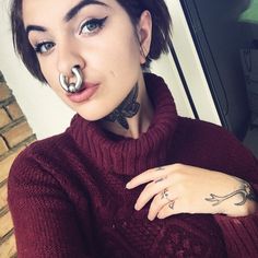 a woman with piercings on her nose wearing a red sweater and black choker