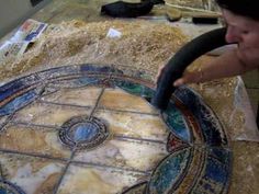 a man sitting at a table with a steering wheel in front of a mosaic design