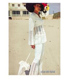 a woman standing on top of a sandy beach next to a white bag and umbrella