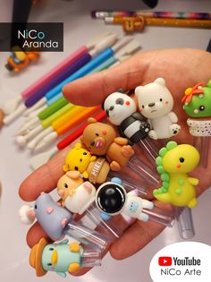 a person is holding many small toy animals in their hand with markers and pens on the table