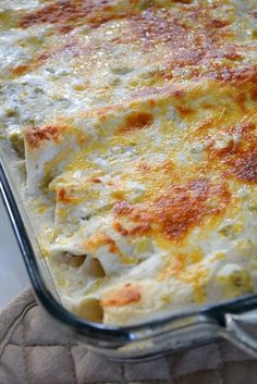 a casserole dish with cheese and sauce in it on a cloth napkin next to a glass container