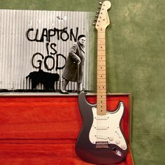 an electric guitar sitting on top of a wooden case next to a sign that says caption is god