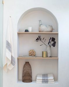 a shelf with towels, vases and other items on it in a bathroom area