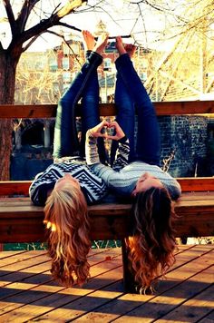 two people are laying on a bench with their hands in the air