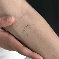 a person holding their arm with a small tattoo on it's left side,