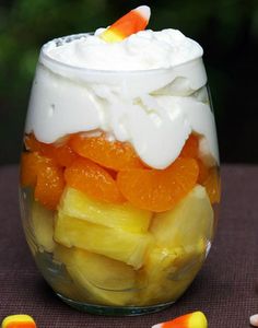 candy corn fruit parfait in a glass jar with marshmallows on the side