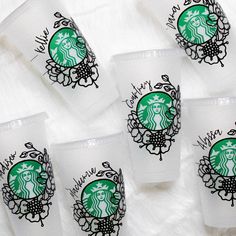 six starbucks cups sitting on top of a white blanket with black and green designs painted on them