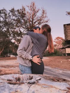 a man and woman kissing in front of a rock formation with trees in the background