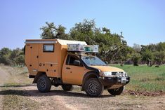 an off road vehicle parked on the side of a dirt road in front of trees