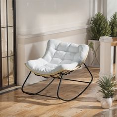 a white chair sitting on top of a hard wood floor next to a potted plant