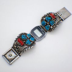 "Native American Navajo handmade impressive sterling silver watch bracelet, decorated with Turquoise and Coral stones and applied figural silver feather motifs. The bracelet has large ornate box type clap. Signed PJ (could be Peterson Johnson). It comes with the Timex watch. This spectacular very good quality bracelet is 6\" long and 1 5/8\" at the widest, total weight is 111.6 grams. The Timex watch is not calculated into the price, it doesn't run (old battery). EA3058" Bohemian Silver Watch Bands As Gift, Bohemian Silver Watch Band As Gift, Bohemian Silver Watch Bands With Bracelet Strap, Bohemian Silver Bracelet Strap Watch Bands, Turquoise And Coral Watches, Southwestern Sterling Silver Bracelet With Turquoise Inlay, Southwestern Style Hand-strung Blue Bracelet, Southwestern Turquoise Inlay Sterling Silver Bracelet, Southwestern Blue Nickel-free Cuff Bracelet