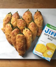 several pastries on a white tray next to a carton of cornbreads