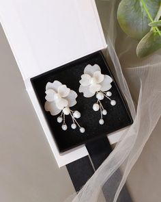 two white flowers and pearls are in a black box