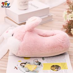 a pink bunny slipper sitting on top of a table next to a white rabbit