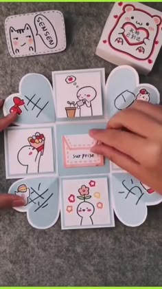 someone's hand is holding onto some cards with drawings on them and the words hello kitty written in different languages